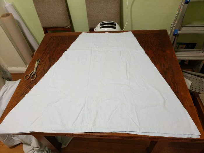 Two petticoat pieces laid out on top of each other on a kitchen table. In the background are two chairs, one of which has a toaster on it.