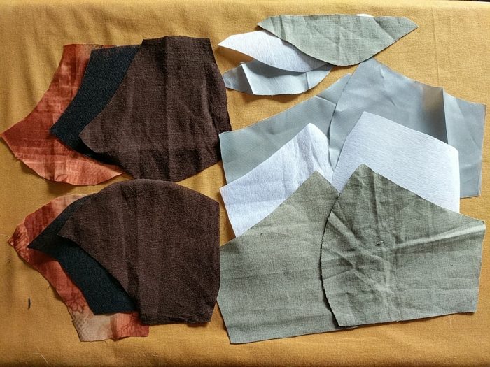 The pieces for two masks, one with a nose piece and one without. Each piece has been cut in three fabrics.