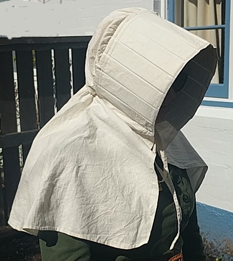 A woman stands in the sunshine wearing a slatted sunbonnet. Her face is in complete shade.