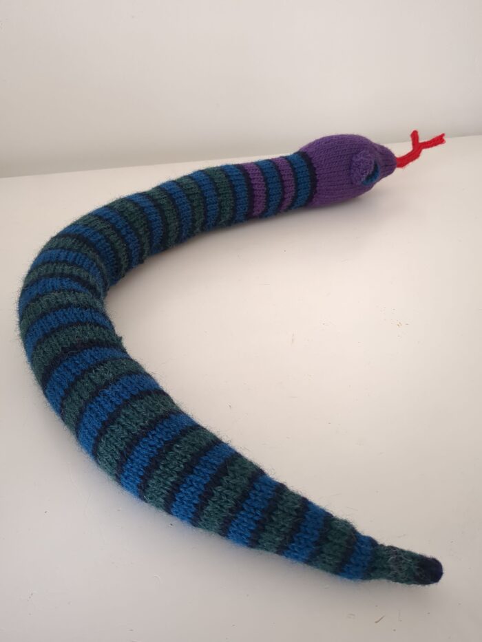 Knitted snake with purple head and blue and green striped body.